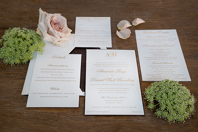 Wedding stationery and invitations lay next to florals. 