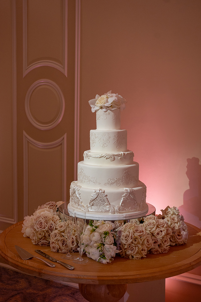 A five-tier white wedding cake designed by Susie's Cakes is the focal point of the pink and brown wedding. 