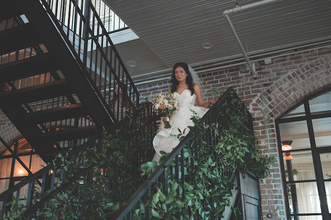 Bride walking down black staircase with greenery for Station 3 wedding.