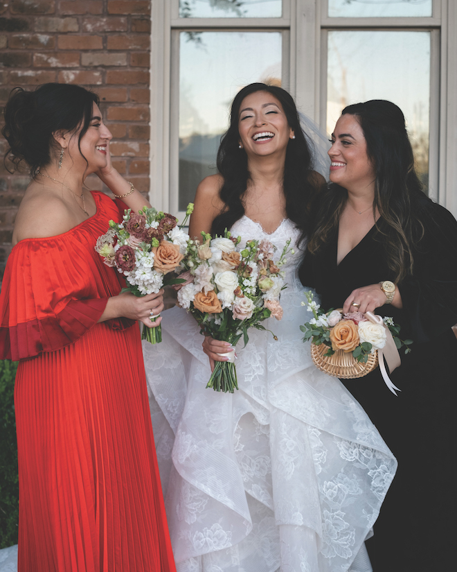 Bride holding bouquet in the middle of two family members.