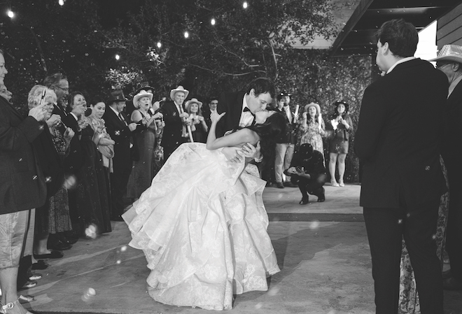 Black and white photo of groom dipping and kissing the bride as they exit their Station 3 wedding. 