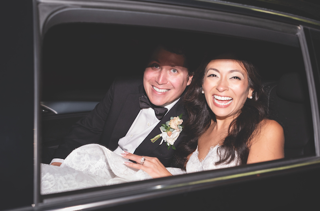 Newlyweds in the window of their getaway car.