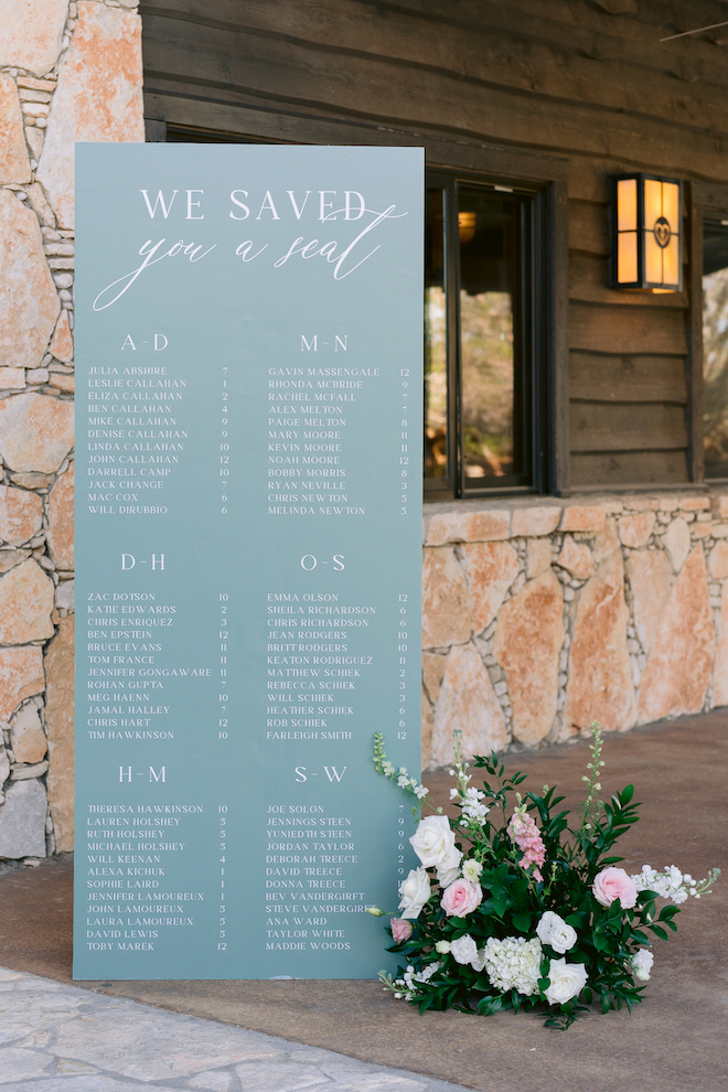 Light blue seating chart next to florals  that reads, "We Saved You a Seat".