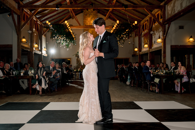 Newlyweds sharing first dance together as guests watch.
