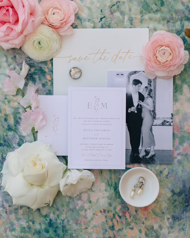 White invitations with pink and white roses surrounding it.