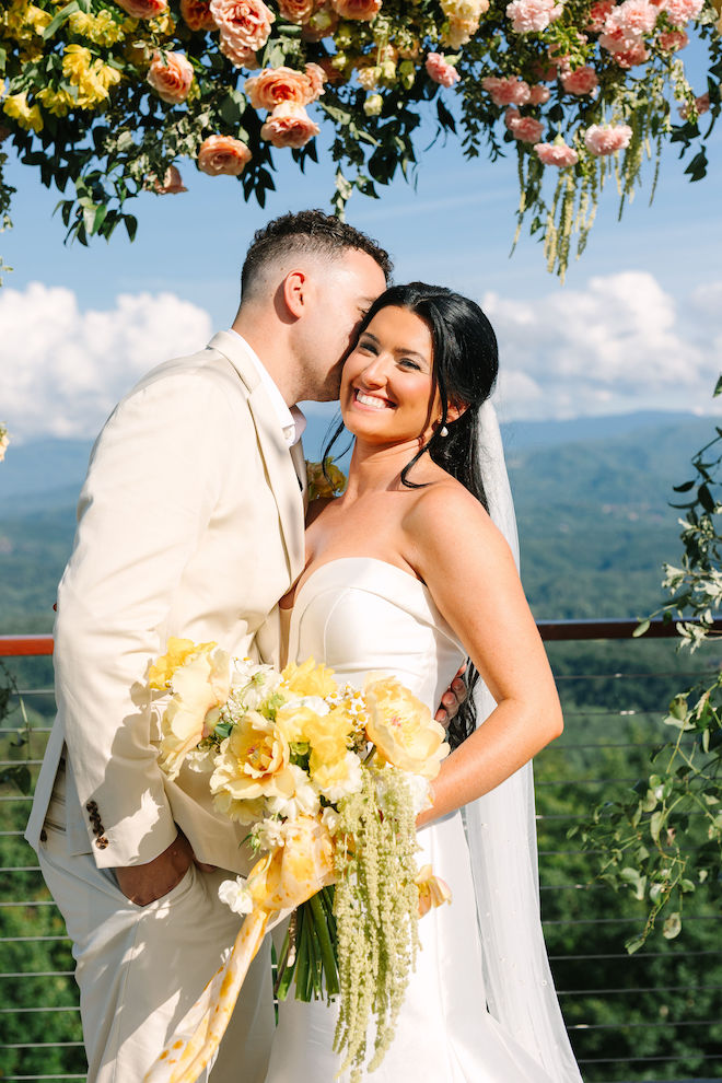 Bride and groom at yellow floral adorned altar.
