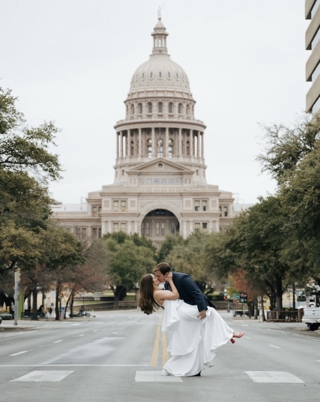 The groom dips the bride in the middle of the road in front of the Texas capital. 