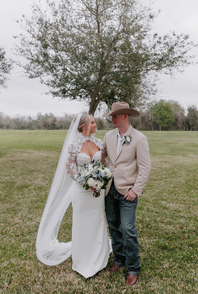 Bride holding blue and white bouquet for summer wedding florals staring at the groom.