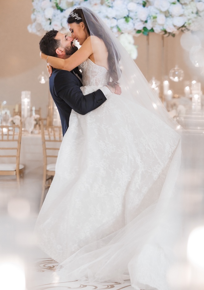 The groom picks up the bride on the dance floor at their Houston reception. 