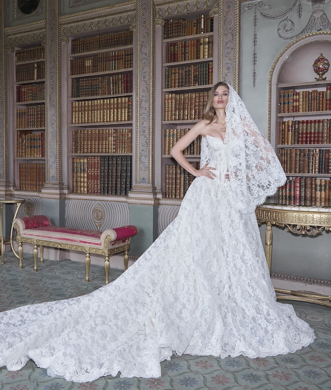 The model wears a cathedral length with a scalloped lace border. 
