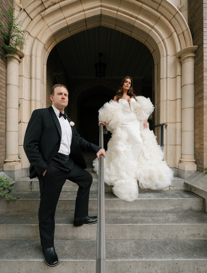 The bride and groom stand on the steps outside of the church in Houston.