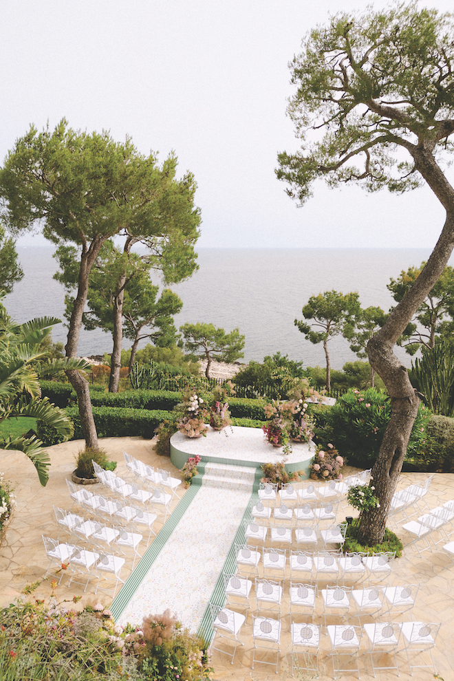 Aerial view of mediterranean sea and with the altar and aisle in front of it adorned in florals.
