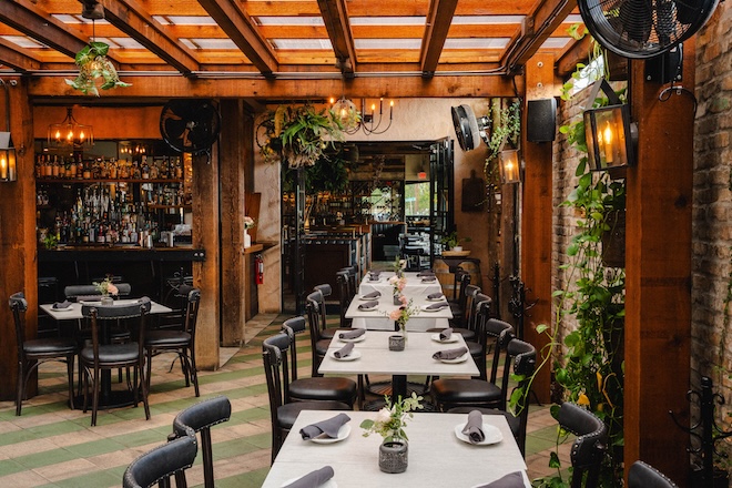The terrace room of Trattoria Sofia features exposed wood and greenery. 