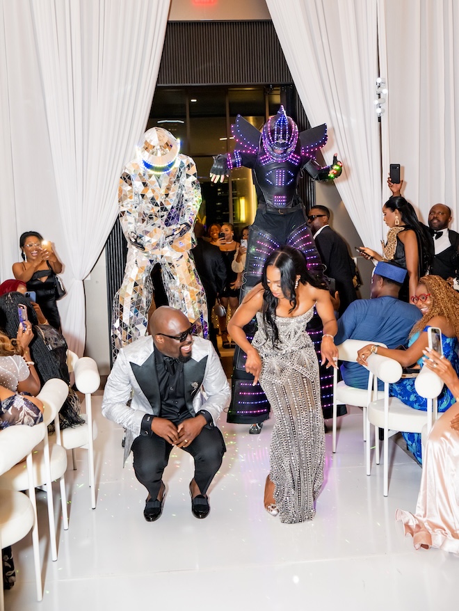 The bride and groom dance into their reception with stilt performers dancing behind them.