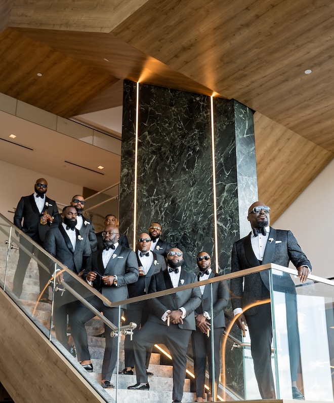 The groom and his groomsmen stand on the staircase of Thompson Houston, by Hyatt. 