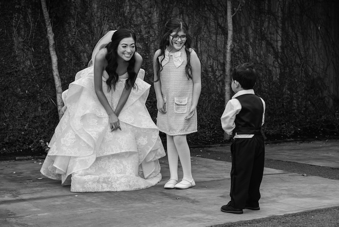 The bride and her niece smile at the ring bearer. 
