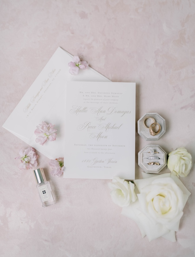 The bride and groom's wedding bands lay next to their wedding stationery. 