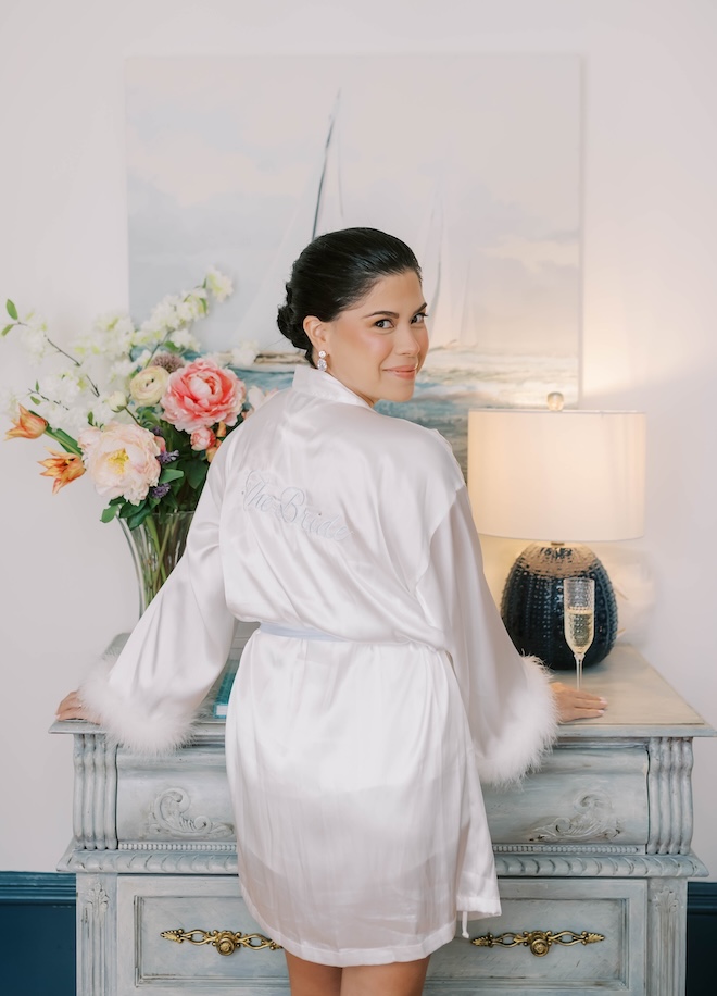 The bride wears a feather lined robe while she gets ready for her Galveston wedding. 