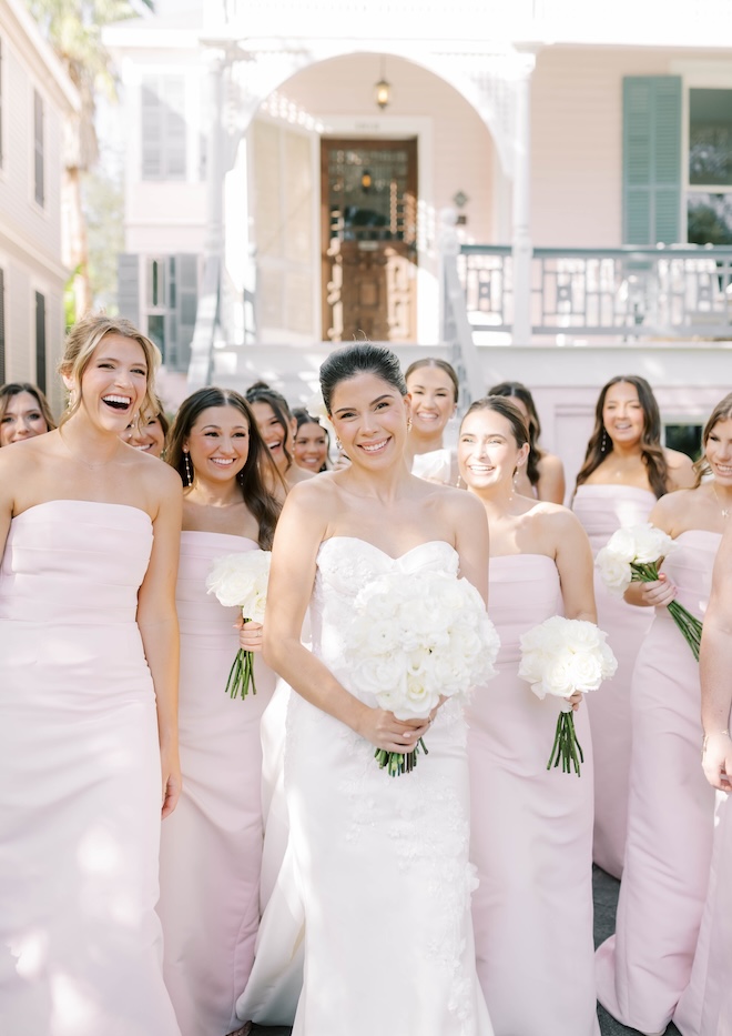 The bride smiles with her bridesmaids outside a home in Gaveston.