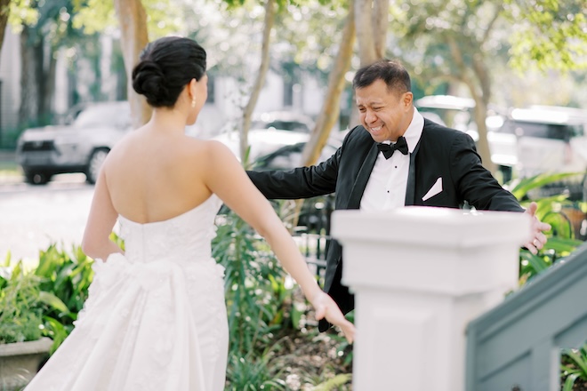 The father of the bride opens his arms to give his daughter a hig during their first look. 
