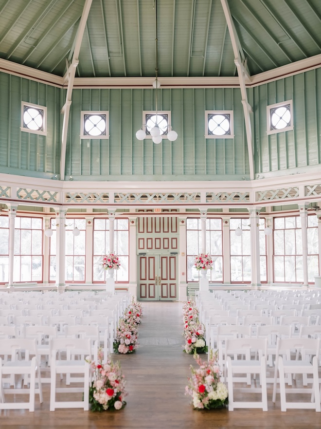 Pink floral arrangements line the aisle at the couple's wedding ceremony. 
