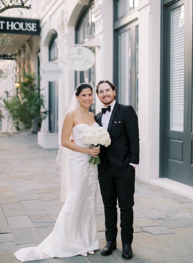 The bride and groom smile in front of The Tremont House in Galveston. 