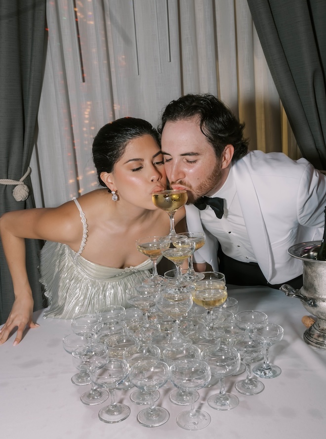 The bride and groom sip Champagne from their Champagne tower. 