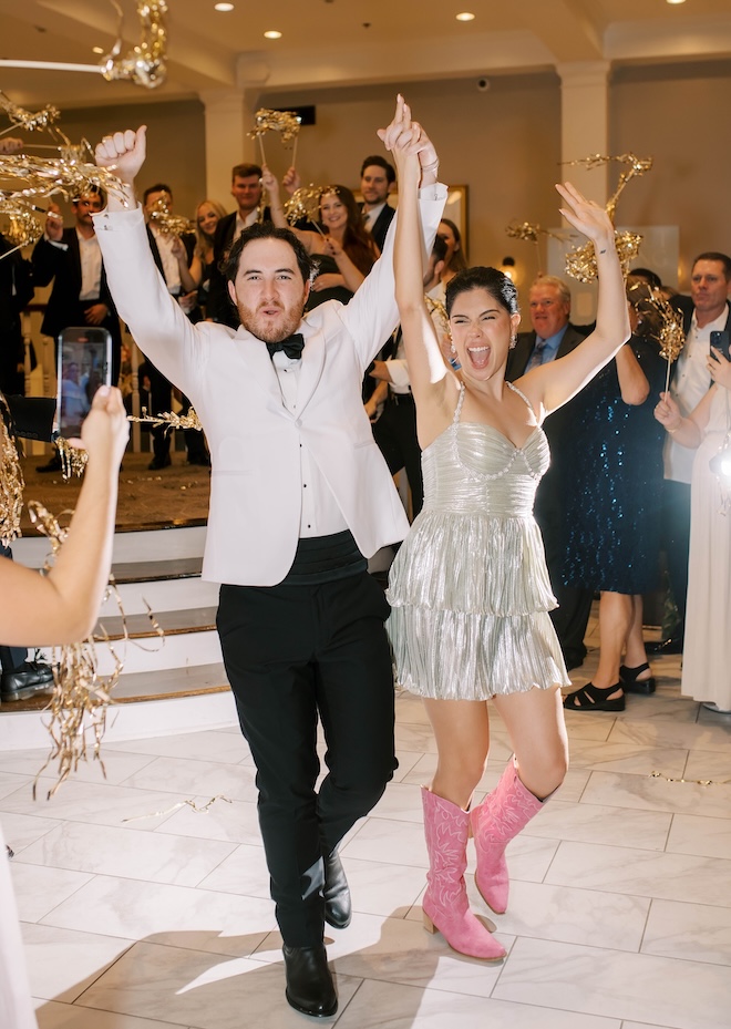 The couple hold hands as they walk through their streamer send-off. 