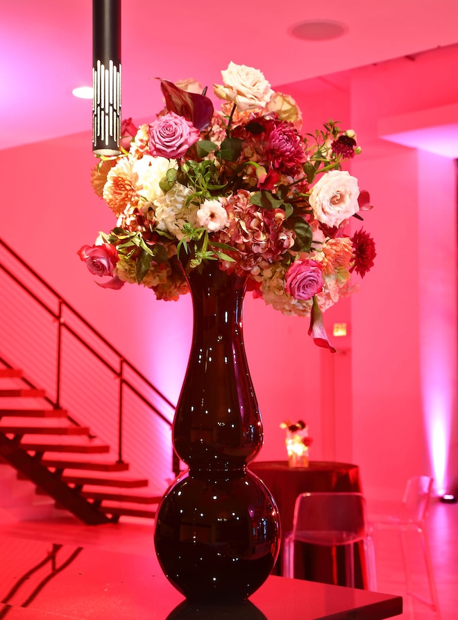 Eggplant and cream colored flowers are arranged into vases for the reception. 