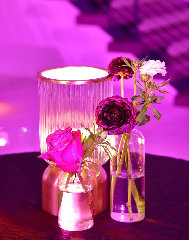 Bud vases with eggplant colored flowers and a lamp decorate the reception tables. 