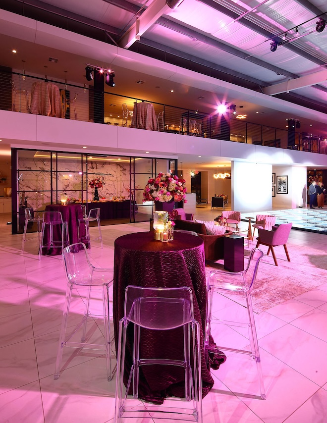 Floral arrangements, eggplant colored linens and acrylic barstools decorate the grand Houston wedding celebration. 