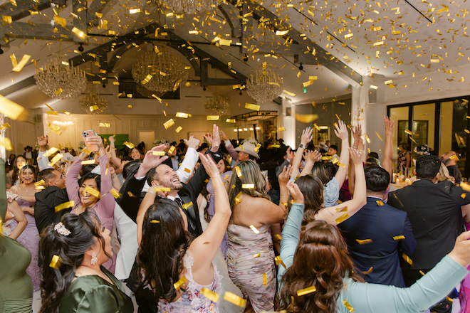 Guests cheering and dancing as gold confetti falls.