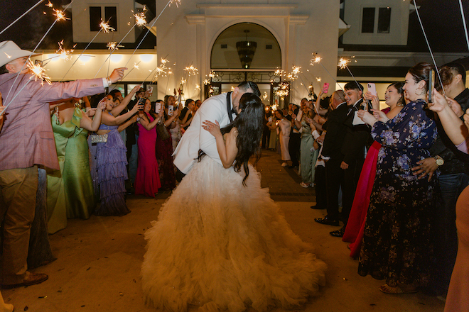 Newlyweds in their sparkler exit kissing after their garden-inspired wedding.