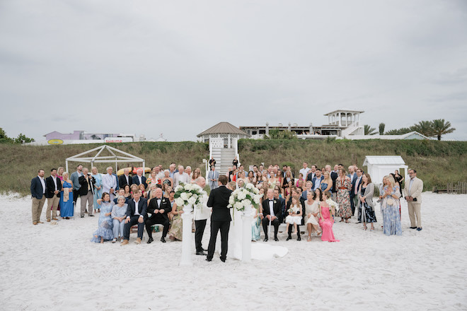 Overview of guests on the beach and the couple at the altar in a an intimate Seaside wedding.