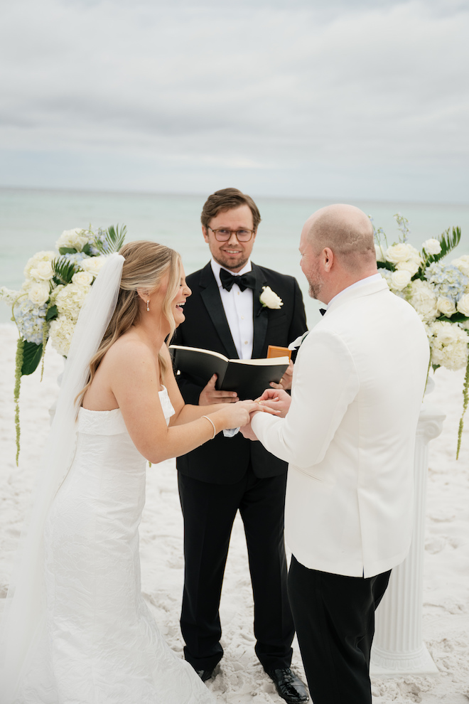 Bride and groom laughing at the altar with the ocean behind them.