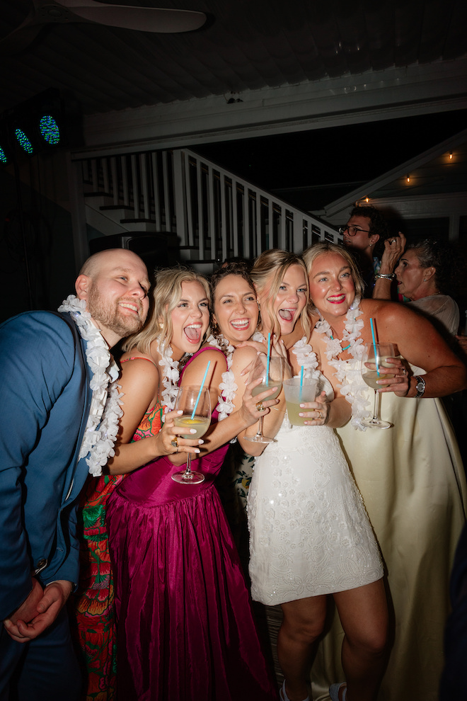 Bride and friends surrounding her while holding drinks at reception.