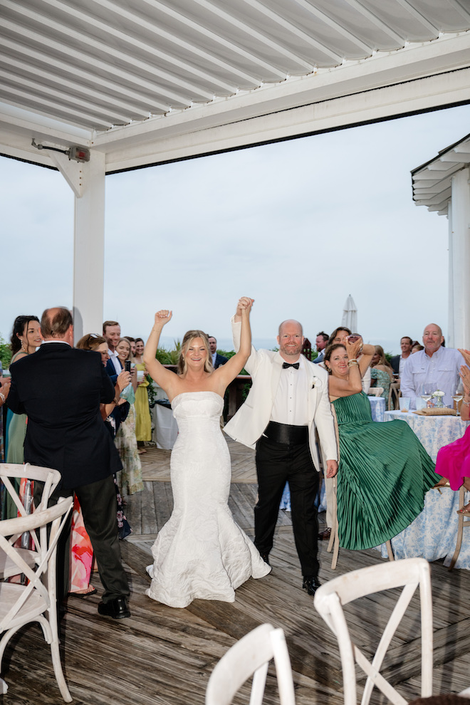 The newlyweds walking into the reception with guests cheering around them.