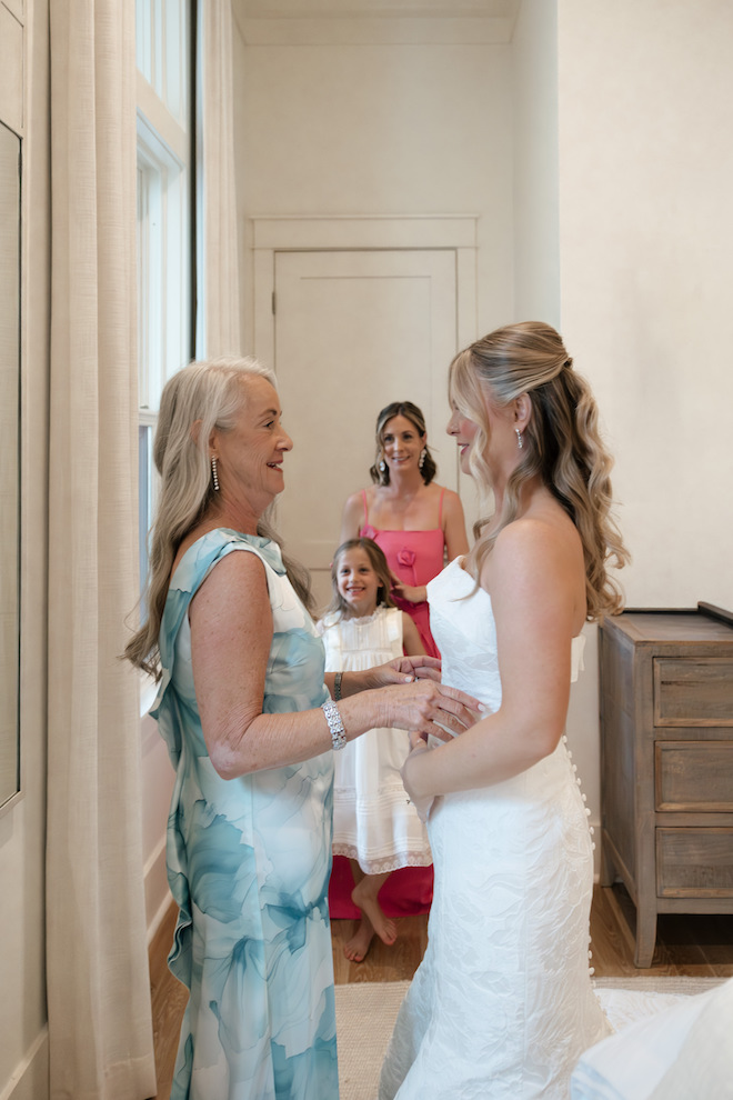 Bride and mother of the bride smiling at each other before in the getting ready room.