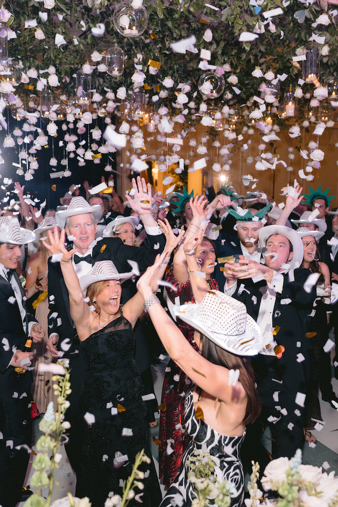 Guests cheering in cowboy hats while white confetti falls.