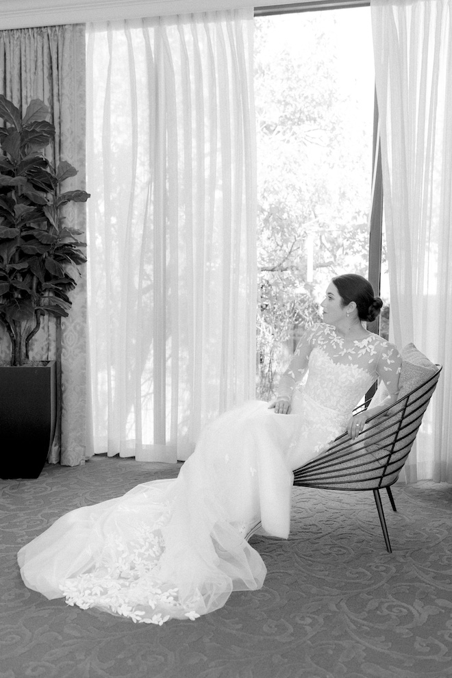 Black and white photo of bride in long stunning dress in front of drapery.