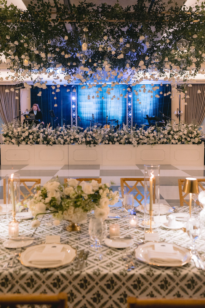 View of the stage, dance floor and reception table surrounded in florals.
