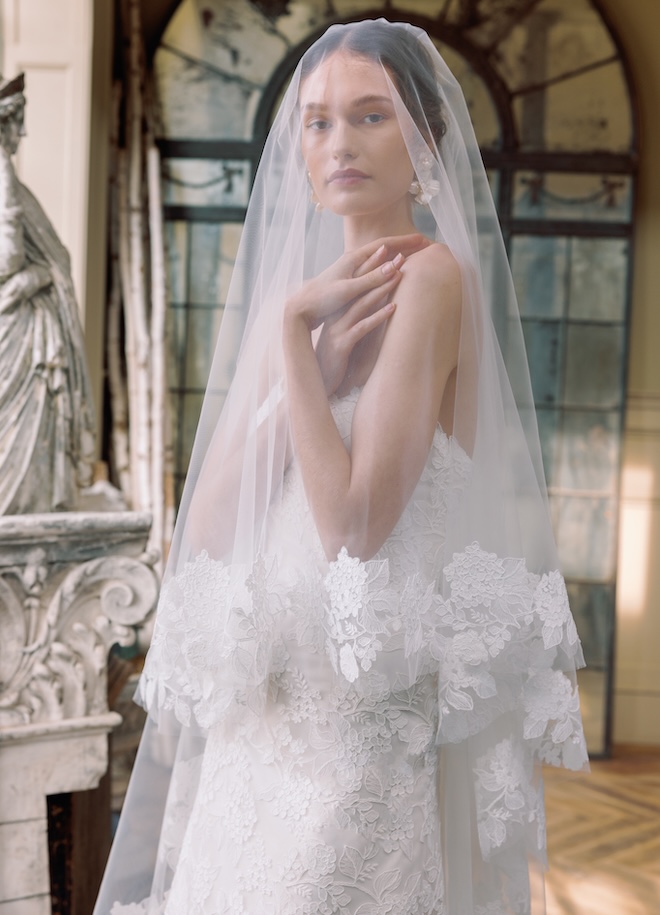 The model wears a lace wedding gown and lace trimmed veil from Sareh Nouri's spring 2026 collection.