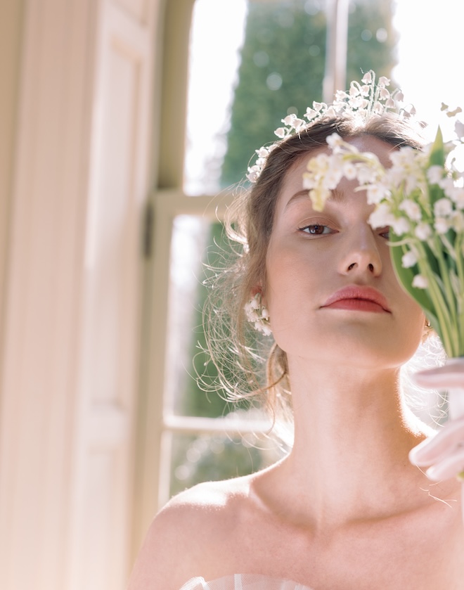 The model holds a bouquet of flowers in front of her face. 