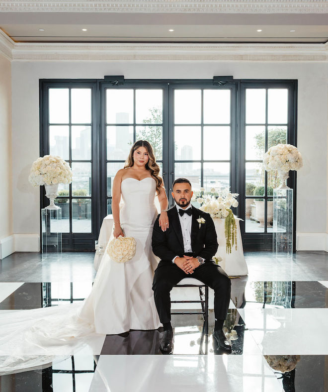 The newlyweds sitting at their table with white florals around them for their black-and-white wedding.