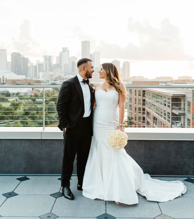 Bride and groom standing on balcony with view of Houston skyline behind them at their black-and-white wedding.