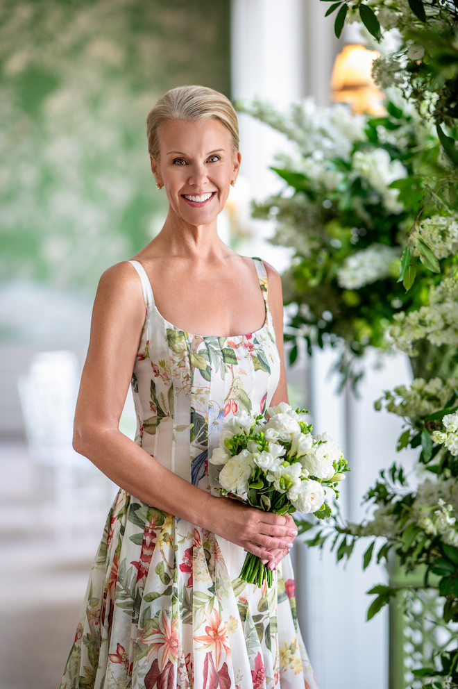 Bride in multicolored floral dress holding white bouquet.