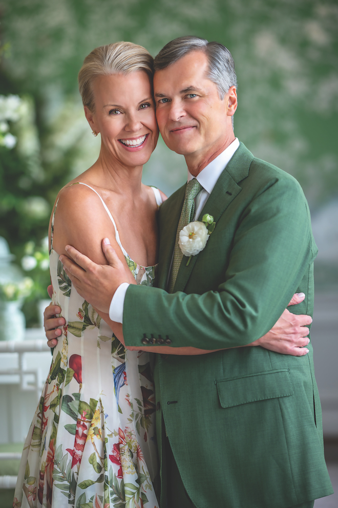 Couple in multicolored floraled dress and green suite in green and white wedding.