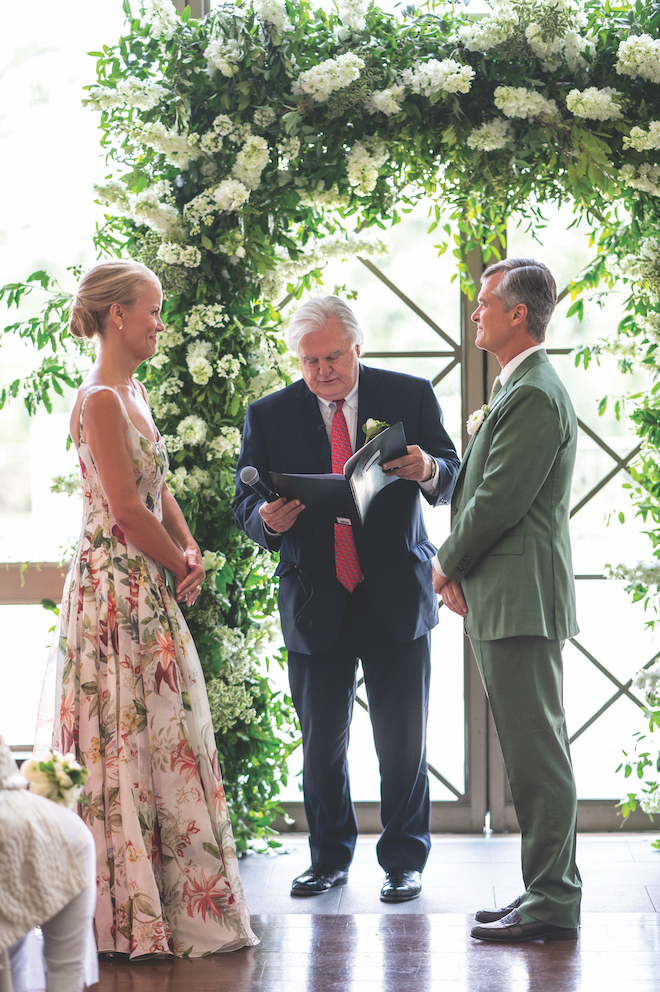 Bride and groom at green and white lush altar to plan your perfect wedding.