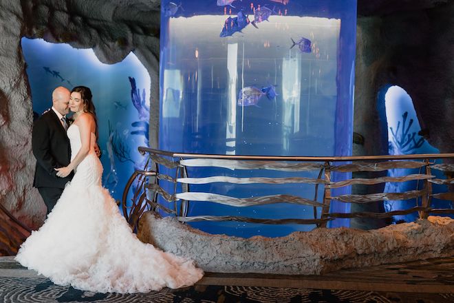 Bride and groom next to cylinder aquarium tank for unique Houston wedding venues.