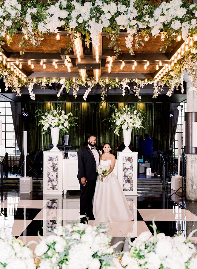 The bride and groom stand on the dance floor at their emerald green wedding at The Astorian.